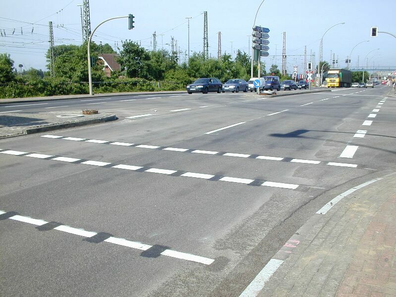 Breite Kreuzung mit mehreren Fahrspuren, Ampeln und Fahrzeugen auf der Straße