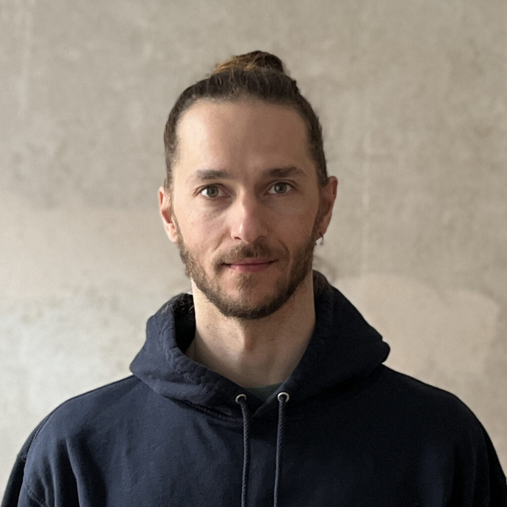 Person mit zusammengebundenem Haar trägt einen dunkelblauen Kapuzenpullover mit dem Logo und Schriftzug "MARK KRONTAL PARTNER"